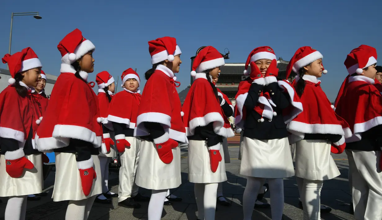 Anak-anak Korea Selatan mengenakan pakaian Santa Claus berjalan di depan Istana Gyeongbokgung, Seoul, Jumat (30/11). The Salvation Army meluncurkan kampanye amal akhir tahun untuk orang miskin. (Jung Yeon-je/AFP)