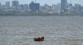 Seorang penjaga membawa kudanya untuk berendam di laut pada suatu hari di musim panas di Mumbai pada tanggal 8 Mei 2024. (Punit PARANJPE/AFP)