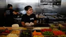 Maria Hidalgo (26) menyiapkan menu makanan di dapur Homegirl Cafe, Los Angeles, Senin (16/7). Kafe yang menyediakan sarapan dan makan siang khas Latin ini menawarkan pengalaman bersantap unik dengan mempekerjakan para mantan anggota geng. (AP/Jae C. Hong)