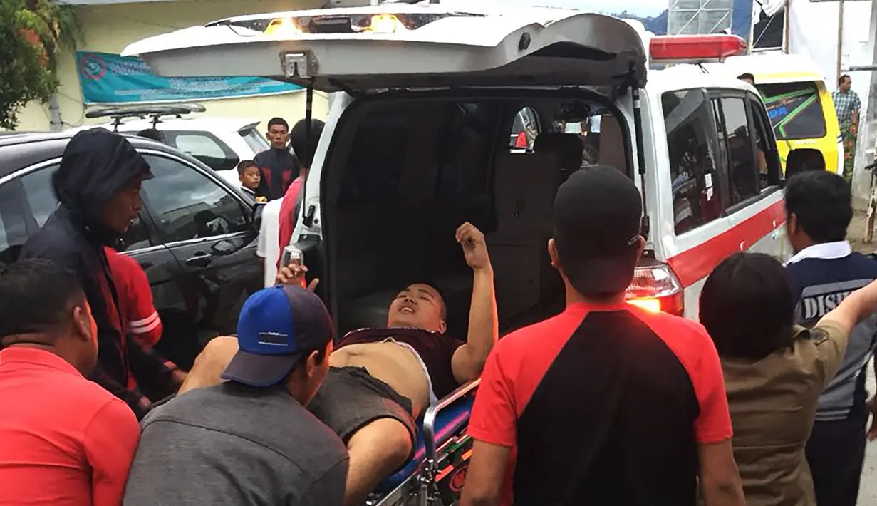 Petugas membawa korban selamat KM Sinar Bangun yang tenggelam di Danau Toba, Sumatera Utara, Senin (18/6). Sejauh ini tim penyelamat telah berhasil menemukan 19 korban, seorang di antaranya meninggal dunia. (AFP Photo/Lazuardy Fahmi)