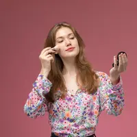 Seorang perempuan sedang mengaplikasikan makeup di bagian pipinya (Foto Dok: Freepik/KamranAydinov).