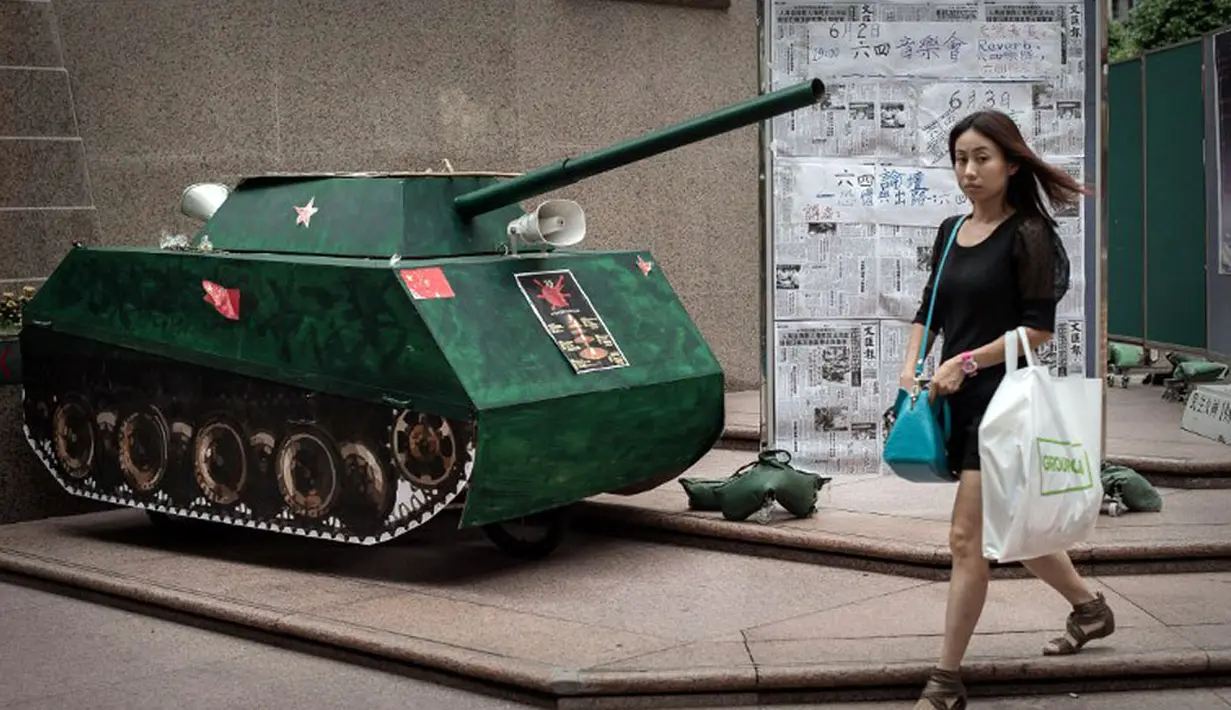 Seorang wanita berjalan melewati replika tank yang ditampilkan di Hong Kong untuk mengenang peristiwa berdarah di Lapangan Tiananmen, Tiongkok, pada 1989 silam, (3/6/2014). (AFP PHOTO/Philippe Lopez)