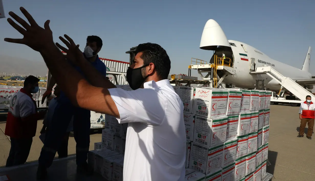 Pekerja membongkar kotak pasokan bantuan dari truk untuk dimuat ke pesawat menuju Beirut, Lebanon, di Bandara Mehrabad di Teheran, Rabu (5/8/2020). Iran mulai mengirimkan makanan, obat-obatan, dan peralatan medis ke Lebanon pascaledakan yang mengguncang pelabuhan di Beirut. (AP Photo/Vahid Salemi)