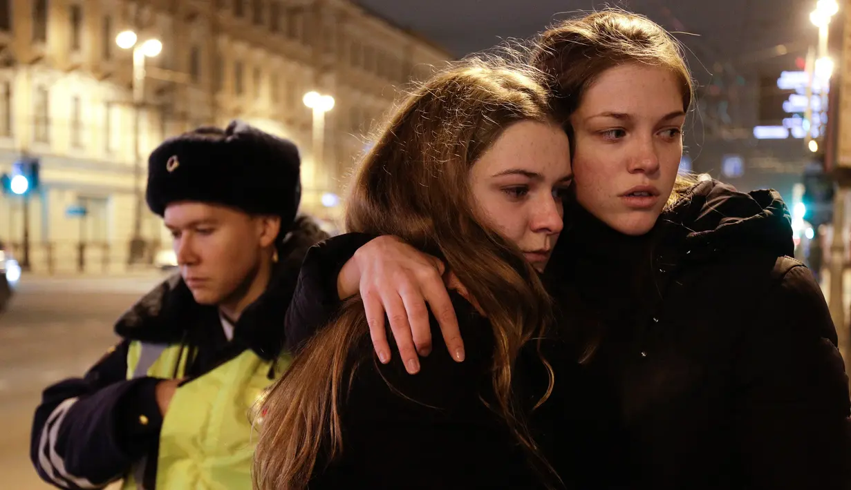 Dua warga berpelukan saat berduka di dekat lokasi ledakan bom di stasiun kereta bawah tanah St. Petersburg, Senin (3/4). Dikabarkan kejadian tersebut menewaskan 10 orang dan menghancurkan sebuah gerbong kereta. (AP Photo / Dmitri Lovetsky)