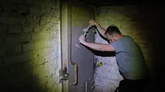 Warga setempat, Jacek (37), menutup pintu ke tempat perlindungan di ruang bawah tanah sebuah bangunan perumahan di Warsawa, Polandia, 19 Oktober 2022. Pertempuran di sekitar pembangkit listrik tenaga nuklir Ukraina dan ancaman Rusia untuk menggunakan senjata nuklir telah membangkitkan kembali ketakutan Eropa akan nuklir. (AP Photo/Michal Dyjuk)
