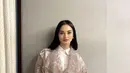 Ririn Ekawati tampil dengan heels putih yang dipadukan dengan kemeja putih dan celana putih di atas outer panjang lace kecokelatannya. Credit: Instagram (@ririnekawati)