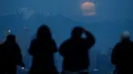 Orang-orang menyaksikan fenomena supermoon atau bulan super dengan latar belakang pusat kota Los Angeles dari Kenneth Hahn Park, Minggu (20/1). Supermoon akhir pekan ini adalah yang pertama terjadi pada tahun 2019 ini. (AP/Ringo H.W. Chiu)