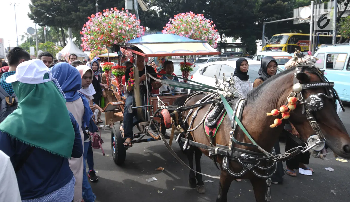 Delman hias membawa pengunjung di sekitar Museum Fatahillah, Jakarta, Rabu (20/6). Libur lebaran 2018, sejumlah PKL memenuhi kawasan Kota Tua Jakarta, akibatnya jalan di sekitar Museum Fatahillah semrawut. (Liputan6.com/Helmi Fithriansyah)