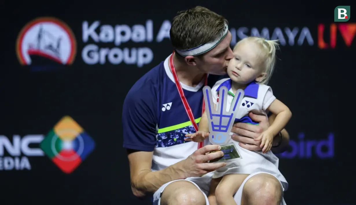 Pebulu tangkis tunggal putra Denmark, Viktor Axelsen, mencium anaknya saat merayakan gelar juara Indonesia Open 2022. (Bola.com/Bagaskara Lazuardi)