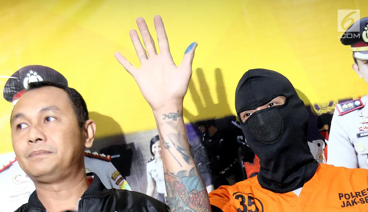Aktor Tora Sudiro (kenakan penutup wajah hitam) melambaikan tangan dalam jumpa pers kepemilikan psikotropika di Mapolres Jakarta Selatan, Jumat (04/08). Tora terancam penjara maksimal 5 tahun. (Liputan6.com/Herman Zakharia)