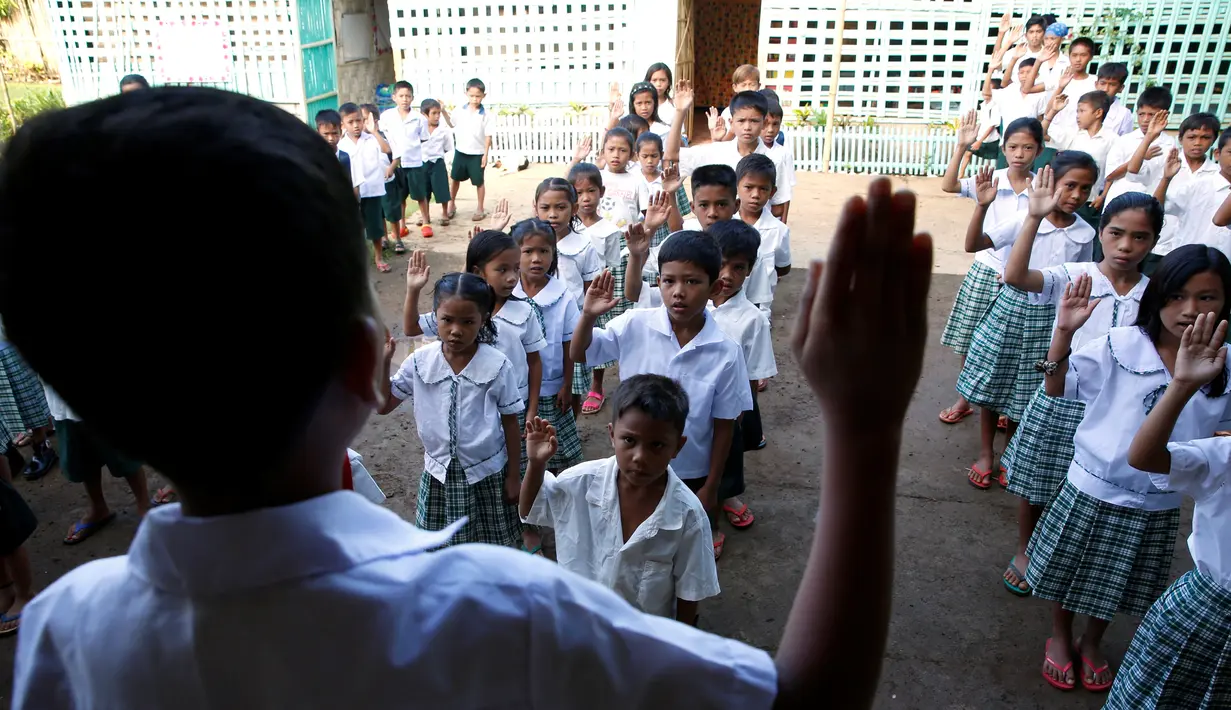 Sejumlah siswa saat mengikuti upacara di sekolah di di sebuah desa terpencil di Montalban, Rizal, Filipina, Senin (13/6). Tidak adanya fasilitas jembatan membuat para siswa mempertaruhkan keselamatannya. (REUTERS/Erik De Castro)