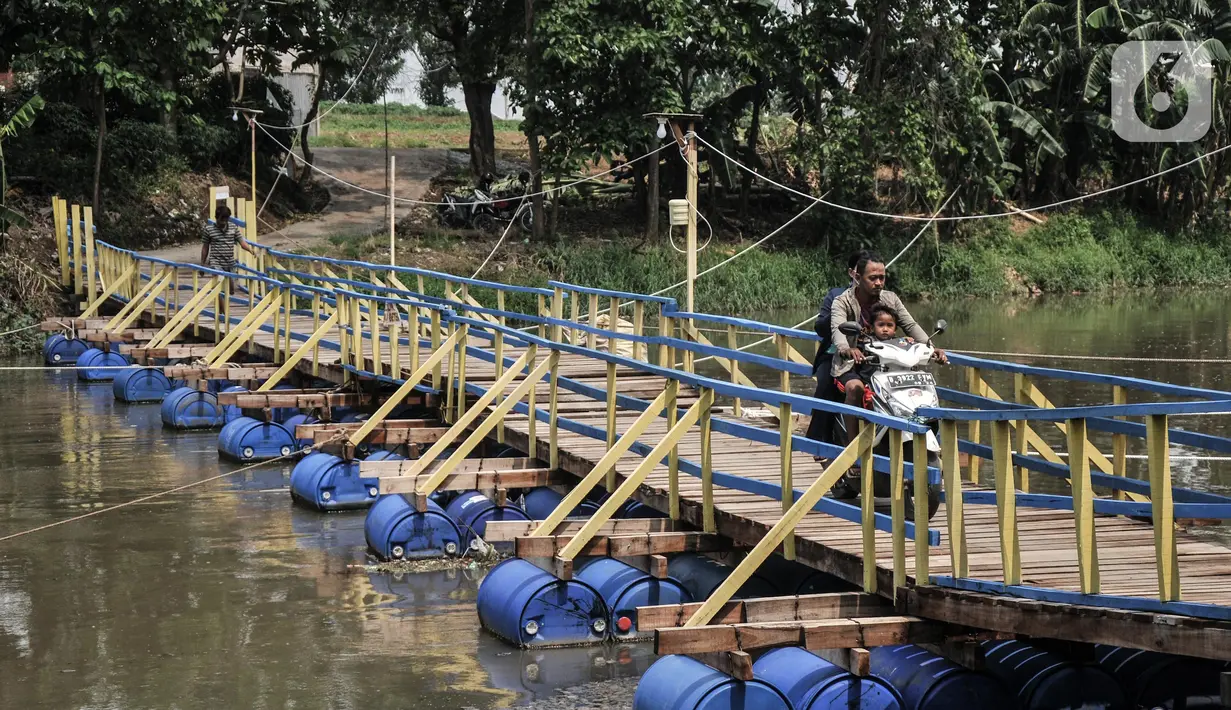 Warga melintasi jembatan apung saat menyeberangi Kali Cikarang Bekasi Laut (CBL) di Desa Sukamekar, Kecamatan Sukawangi, Kabupaten Bekasi, Jawa Barat, Kamis (17/2/2022). (merdeka.com/Iqbal S. Nugroho)