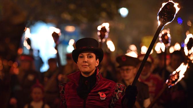 Peserta melakukan pawai melintasi jalan dalam perayaan Bonfire Night di Sussex Timur, Inggris, Selasa (5/11/2019). Setiap tahunnya pada tanggal 5 November, warga Inggris menggunakan kostum, berdandan, berkumpul, lalu melakukan pawai ke seluruh penjuru kota sambil membawa obor. (Ben STANSALL/AFP)