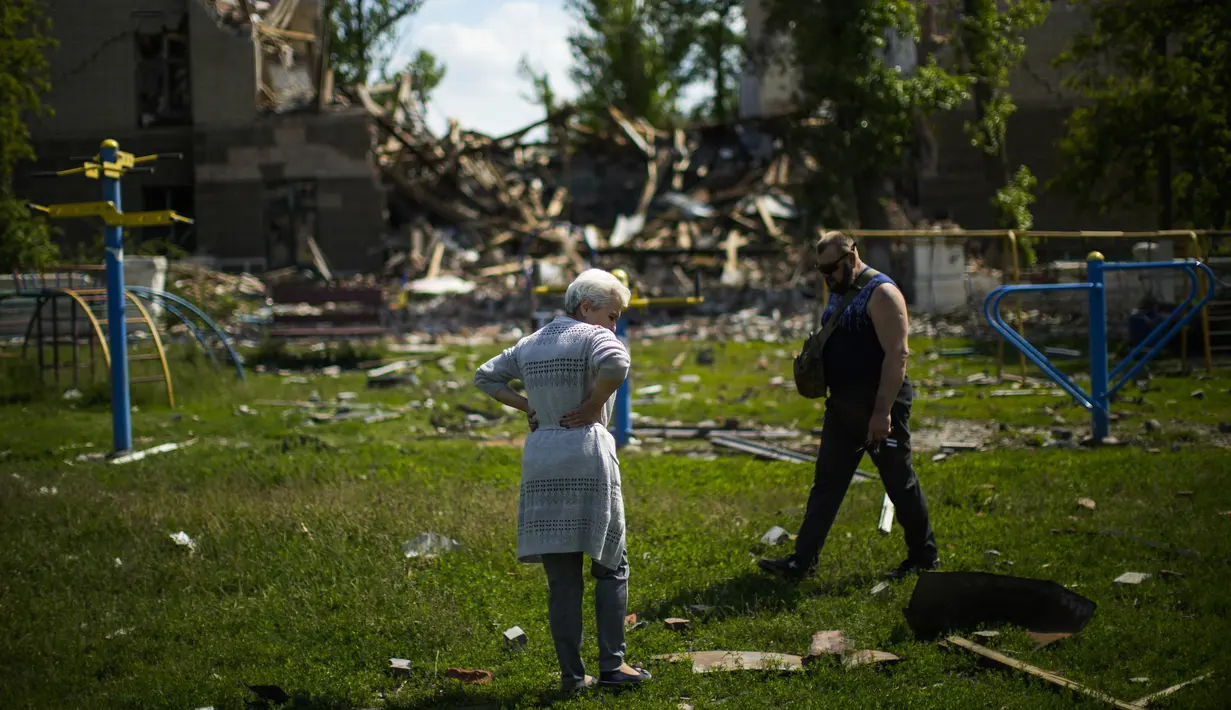 <p>Penduduk setempat berdiri di samping sebuah sekolah yang hancur dalam pemboman Rusia di Bakhmut, Ukraina timur, Selasa (24/5/2022). Kota Bakhmut telah mengalami peningkatan serangan artileri, terutama selama seminggu terakhir, ketika pasukan Rusia mencoba untuk terus maju mengepung kota Sieverodonetsk di timur laut. (AP Photo/Francisco Seco)</p>