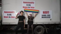 Peserta parade penyuka sesama jenis berfoto dengan poster slogan anti-gay dalam acara 'Gay Pride' di Seoul, Korea Selatan (15/7). Sekitar 10.000 warga korsel turun ke jalan untuk merayakan parade bagi kaum LGBT. (AFP Photo/Ed Jones)