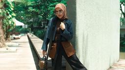 Gaya penampilan Irish Bella Menggunakan busana kombinasi warna cokelat, navy dan hitam ini juga tak lepas dari sorotan. Bahkan, ia terlihat memilih memadukan penampilannya dengan hijab serta tas dengan warna senada. (Liputan6.com/IG/@_irishbella_)