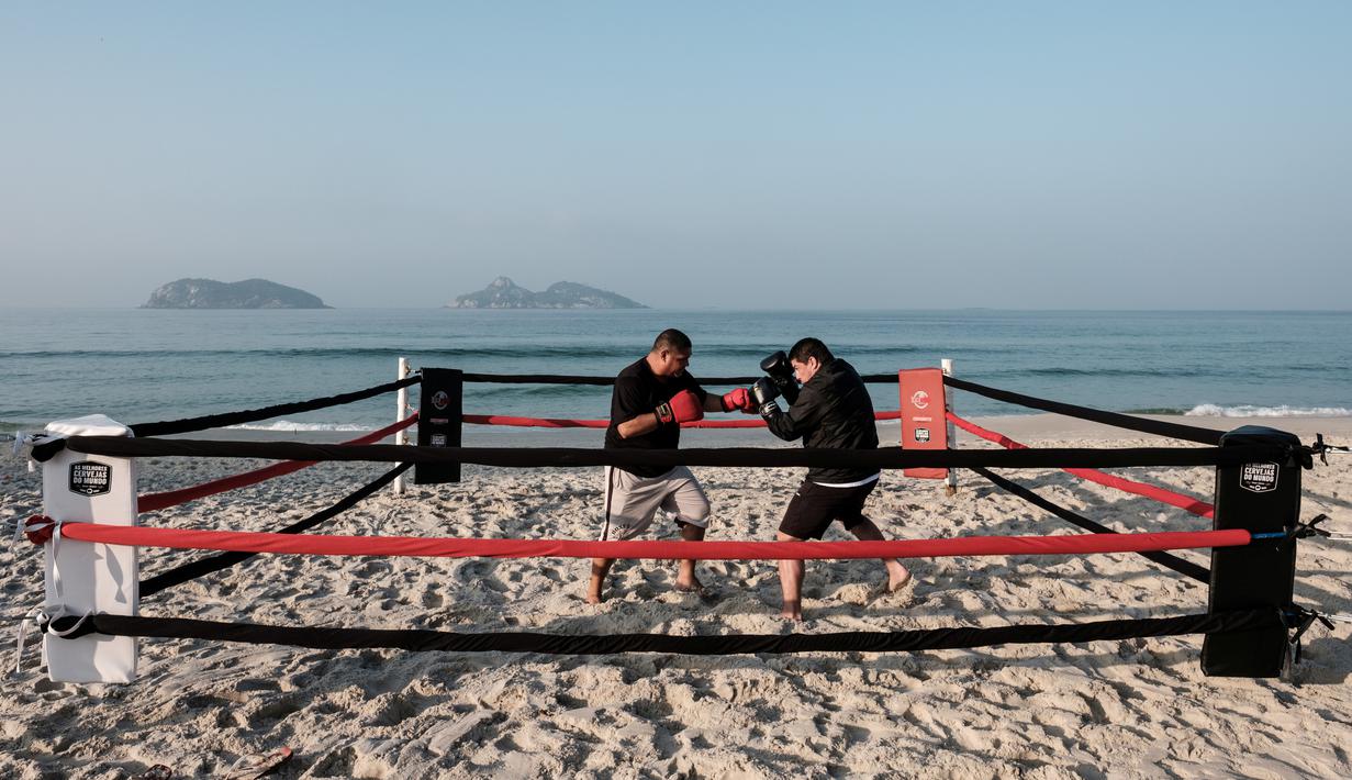  Pelatih tinju, Moacyr Lima (kiri), melatih Leandro Guignoni di ring tinju yang terletak di Pantai Pepe, Rio de Janeiro, Brasil, (26/7/2016). (AFP/Yasuyoshi Chiba)