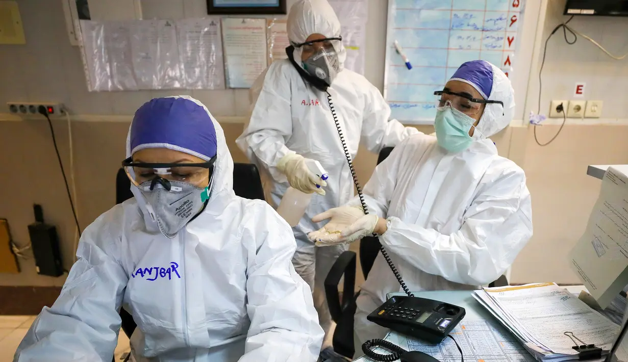 Seorang petugas medis membersihkan tangan rekannya di sebuah rumah sakit yang menangani pasien virus corona atau COVID-19 di Teheran, Iran, Minggu (1/3/2020). Sejauh ini, Iran mencatat ada 1.501 kasus virus corona dengan 66 korban meninggal. (Koosha Mahshid Falahi/Mizan News Agency via AP)