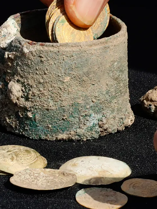 Sebuah bejana perunggu berisi koin emas kuno dan anting-anting ditemukan di sebuah situs penggalian di kota Mediterania Kaisarea, Israel, Senin (3/12). Koin-koin emas dalam bejana tersebut diperkirakan dibuat pada akhir abad ke-11. (JACK GUEZ/AFP)