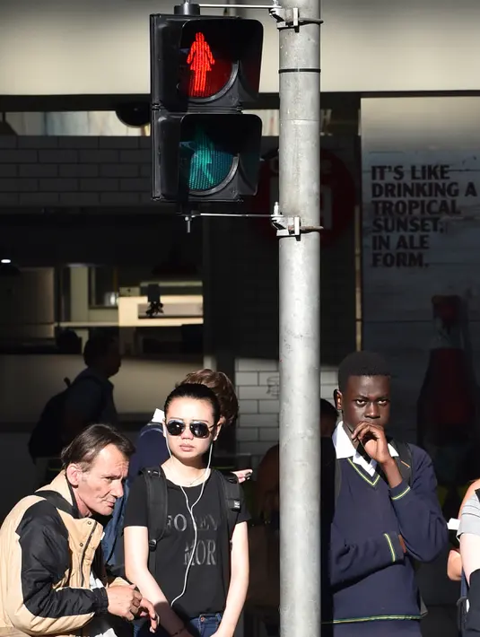 Warga menunggu dibawah lampu lalulintas bertanda perempuan saat peringatan hari perempuan Internasional di Swanston Street dekat Stasiun Flinders Street, Melbourne, Australia, Rabu (8/3). (AFP Photo / Paul Crock)