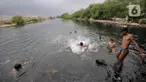 Anak-anak berenang di rawa pesisir Muara Baru, Cilincing, Jakarta, Minggu (15/8/2021). Anak-anak setempat memanfaatkan rawa sebagai wahana berenang akibat keterbatasan lahan bermain di wilayah pesisir tersebut. (merdeka.com/Iqbal S Nugroho)