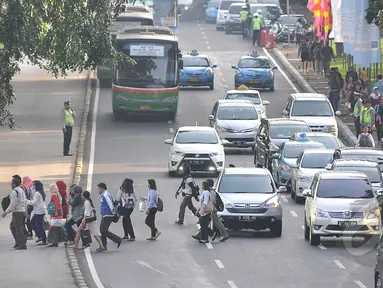 Sejumlah pekerja menyebrang jalan di kawasan Sudirman, Jakarta, Rabu, (22/4/2015). Adanya pengalihan arus untuk KAA membuat mereka terpaksa jalan kaki. (Liputan6.com/Johan Tallo)