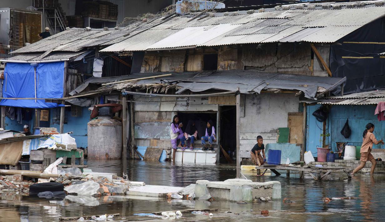 Genangan air akibat banjir rob masuk hingga ke permukiman warga, menyebabkan aktivitas masyarakat terganggu. Tampak dalam foto, anak-anak bermain saat air pasang membanjiri pemukiman mereka di Muara Baru, Jakarta, Sabtu 6 Desember 2025. (ADITYA IRAWAN/AFP)