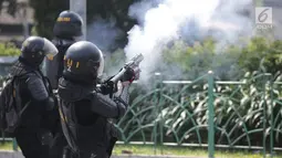 Polisi menembakan gas air mata ke arah massa aksi demo di Petamburan, Jakarta Barat, Rabu (22/5/2019). Hingga pukul 12.15 WIB, massa masih saling berhadap-hadapan dengan polisi di lokasi tersebut. (Liputan6.com/Faizal Fanani)