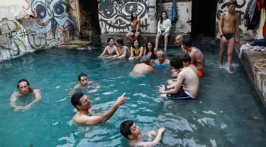 Wisatawan berendam di kolam air panas di ujung selatan Dataran Tinggi Golan yang dianeksasi Israel, dekat perbatasan dengan Yordania, 1 Maret 2019. Kolam dengan air panas itu berasal dari aliran pipa pengeboran di Lembah Hula. (MENAHEM KAHANA/AFP)