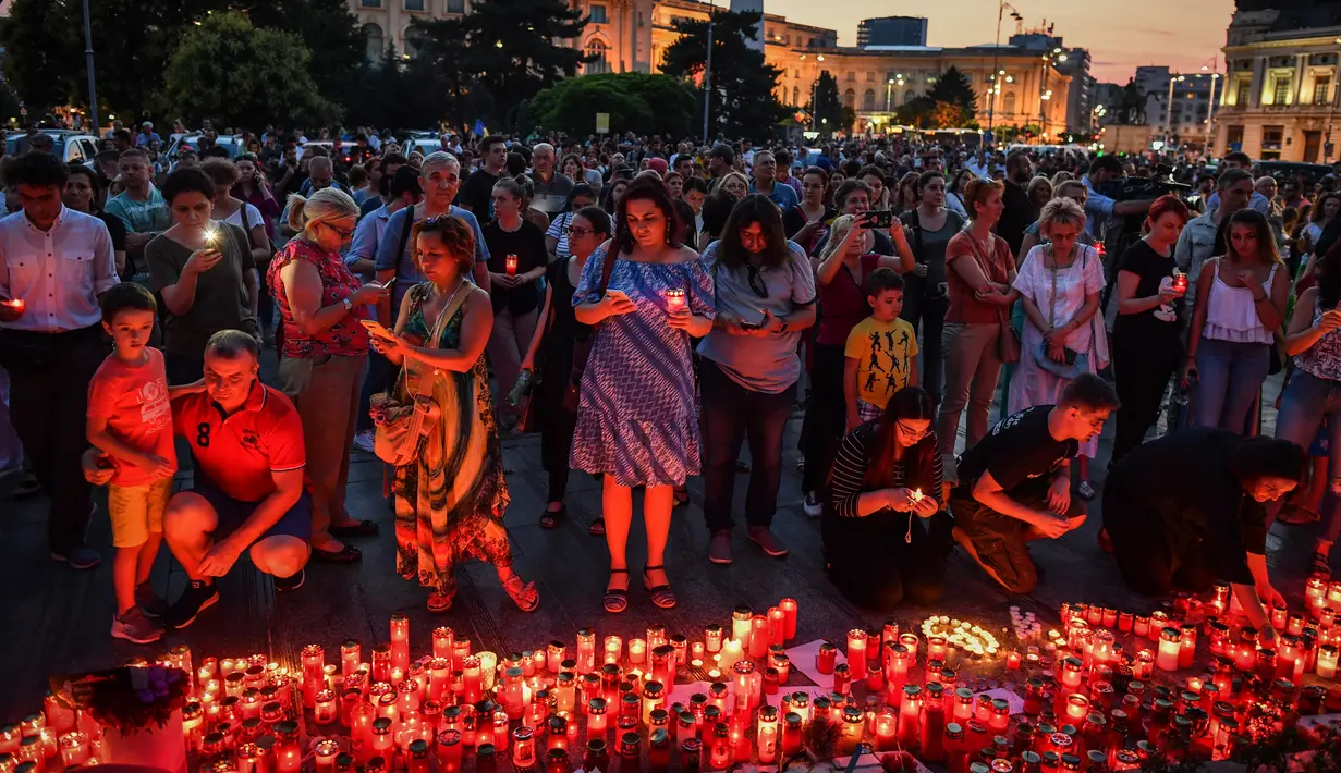 Warga menyalakan lilin untuk memperingati gadis berusia 15 tahun Alexandra yang terbunuh di depan Kementerian Dalam Negeri Rumania di Bucharest (27/7/2019). Alexandra diculik pada Rabu (24/7) ketika ia menumpang pulang ke Dobrosloveni di Rumania selatan, kata polisi.  (AFP Photo/Daniel Mihailescu)