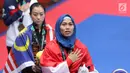 Atlet Taekwondo putri Indonesia, Defia Rosmaniar saat di podium kemenangan Final Women Individual Poomsae di JCC, Jakarta, Minggu (19/8). Defia Rosmaniar meraih emas usai menumbangkan Salahshouri Marjan dari Iran. (Liputan6.com/Helmi Fithriansyah)