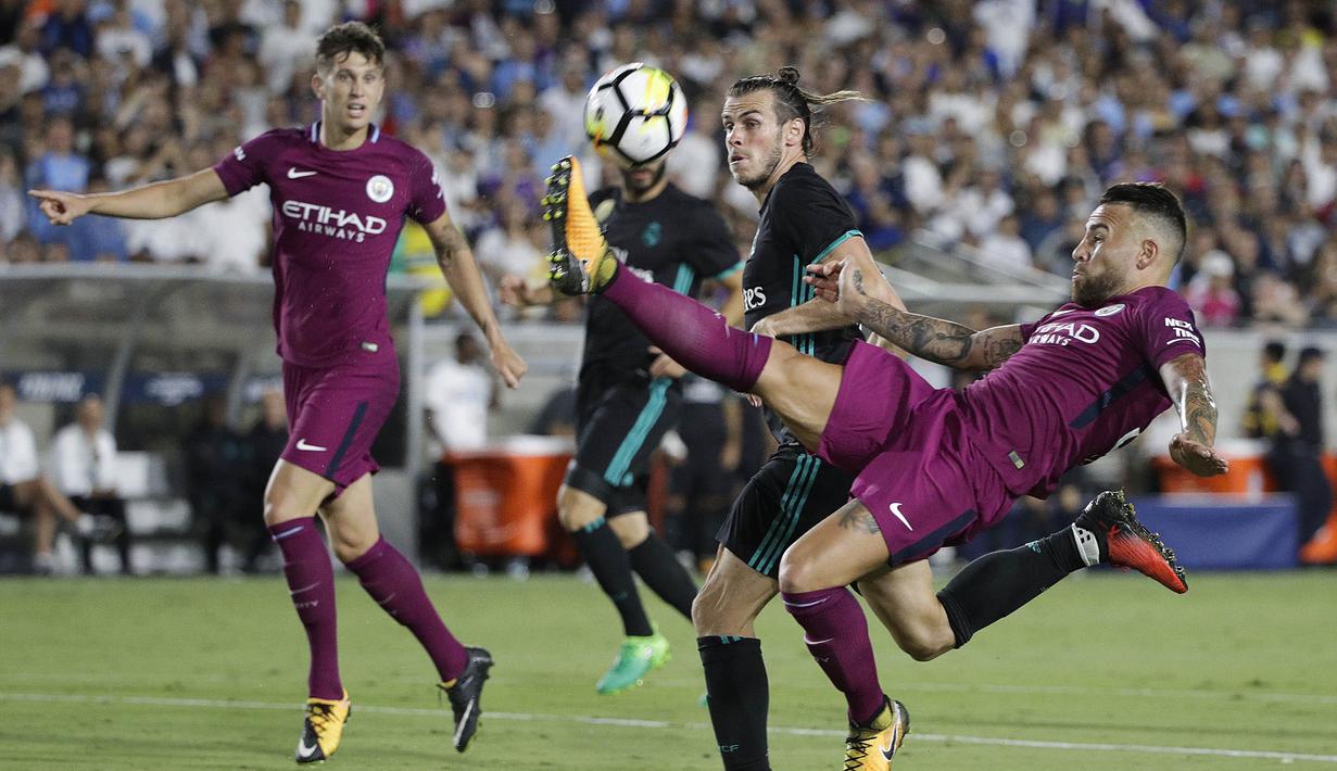 Bek Manchester City, Nicolas Otamendi, membuang bola dari jangkauan gelandang Real Madrid, Gareth Bale, pada laga ICC di Stadion Memorial Coliseum, California, Rabu (26/7/2017). Manchester City menang 4-1 atas Real Madrid. (AP/Jae C Hong)