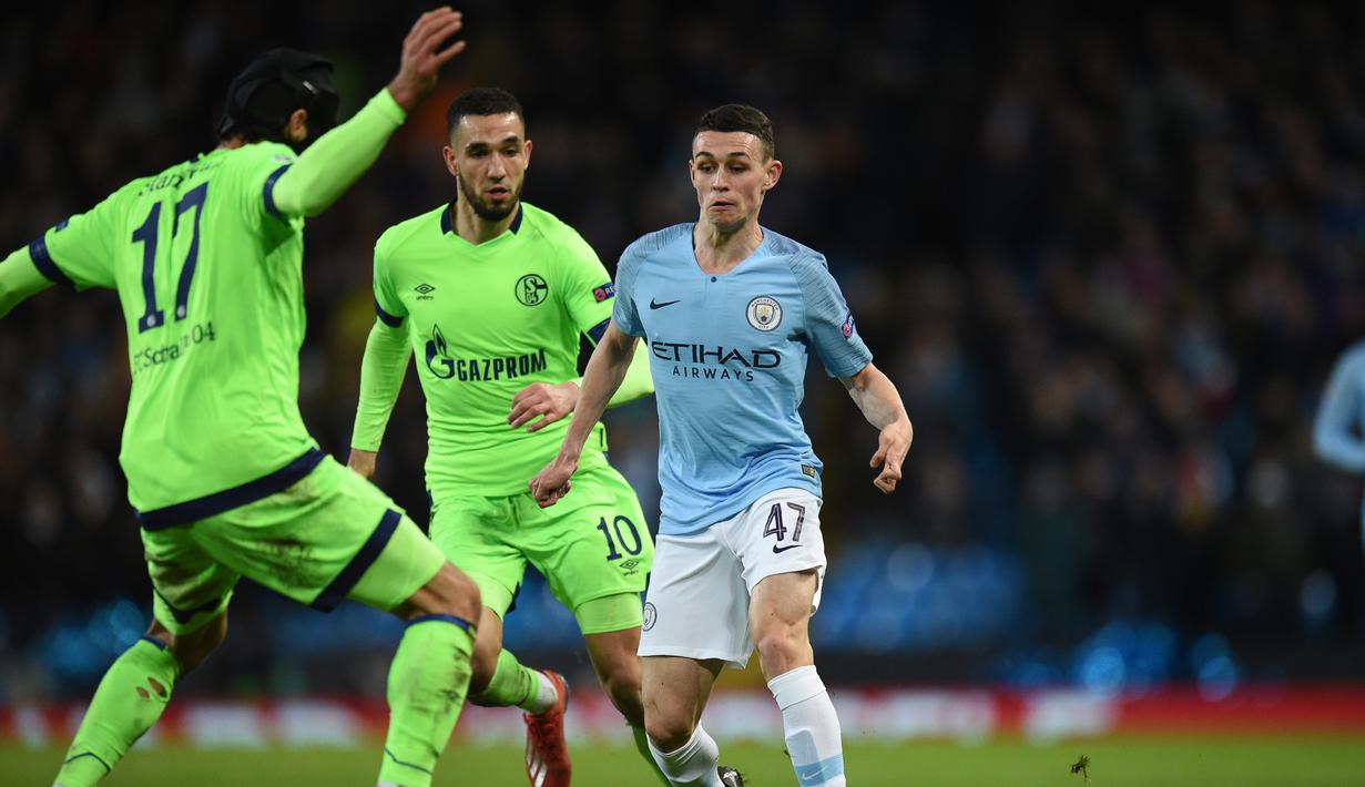Pemain Man City, Phil Foden mencoba melewati hadangan pemain Schalke pada leg kedua, babak 16 besar Liga Champions yang berlangsung di Stadion Etihad, Manchester, Rabu (13/3). Man City menang 7-0 atas Schalke. (AFP/Oli Scarff)