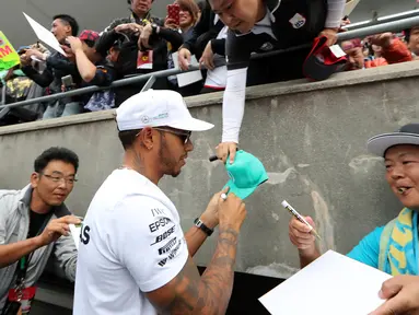 Pembalap Mercedes Lewis Hamilton memberi tanda tangan disebuah topi penggemarnya jelang Grand Prix F1 di Sirkuit Suzuka, Jepang (5/10). F1 GP Jepang akan digelar pada tanggal 8 Oktober mendatang. (AP Photo/Eugene Hoshiko)