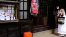 Pengunjung yang mengenakan masker berdiri di sebelah patung-patung maneki-neko di Kuil Gotokuji, Tokyo, Jepang, Rabu (10/6/2020). Kuil Gotokuji terkenal karena dipercaya sebagai tempat kelahiran maneki-neko, kucing pembawa keberuntungan. (Philip FONG/AFP)