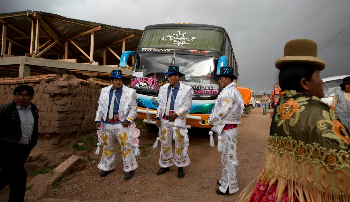 Sejumlah lelaki mengenakan kostum bersiap mengikuti karnaval Anata Andina (Andean karnaval) di Caquiaviri, Bolivia, Selasa (17/1). Dalam acara tersebut sejumlah orang mengenakan kostum dan topeng memenuhi jalan Provinsi Caquiaviri. (AP Photo/Juan Karita)