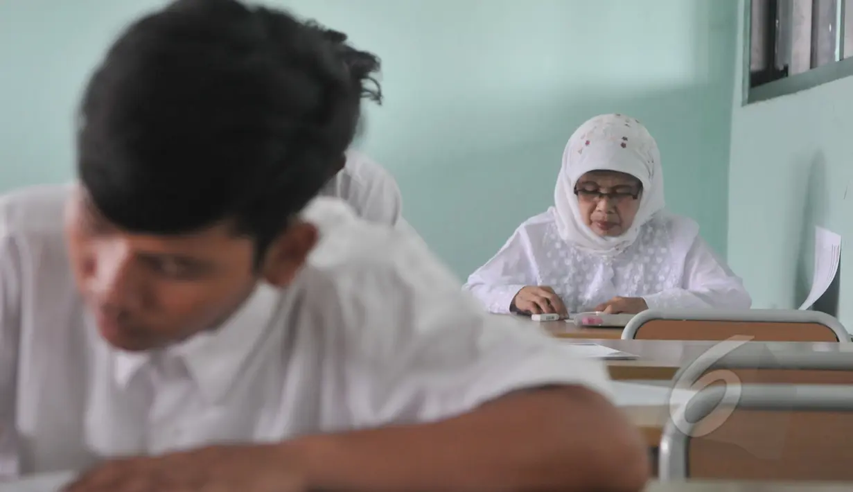 Seorang ibu terlihat mengerjakan soal Ujian Nasional (UN) kesetaraan paket B di SMPN 80 Jakarta, Senin (4/5/2015). Sebanyak 378 peserta, termasuk peserta berusia lanjut mengikuti UN di hari pertama tersebut. (Liputan6.com/Johan Tallo)