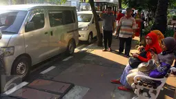 Sejumlah pekerja menunggu minibus plat hitam yang berfungsi sebagai angkutan umum di kawasan Sarinah, Jakarta, Sabtu (27/6/2015). Jasa angkot gelap menjadi favorit di kawasan tersebut karena tarif yang relatif terjangkau. (Liputan6.com/Johan Tallo)