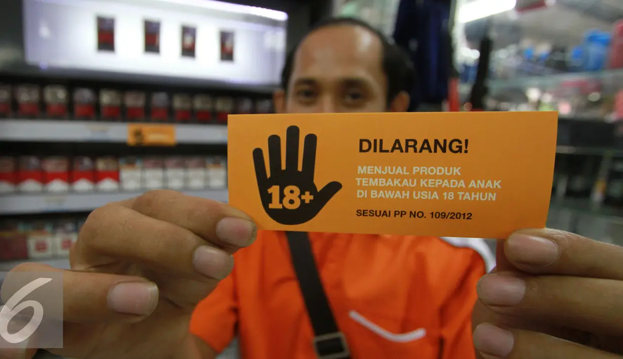 Seorang lelaki menunjukkan stiker larangan menjual rokok kepada anak di bawah usia 18 tahun, Jakarta, Rabu (30/11). Sampoerna memperkuat komitmen untuk mencegah akses penjualan rokok kepada anak-anak (Liputan6.com/Ferry Pradolo)