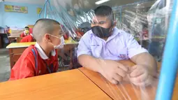 Para siswa saling mengobrol dengan dibatasi lembaran plastik di sebuah sekolah di Bangkok, Thailand (1/7/2020). Sekolah-sekolah di Thailand telah dibuka kembali pada Rabu (1/7). (Xinhua/Rachen Sageamsak)