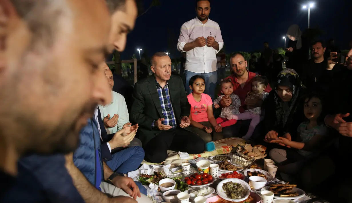 Presiden Turki, Tayyip Erdogan berdoa sebelum berbuka puasa bersama warga di sebuah taman di Istanbul pada Senin (27/5/2019). Buka puasa bersama tersebut dilakukan Erdogan agar lebih dekat dengan warganya. (Murat Kula/Presidential Press Office/Handout via REUTERS)