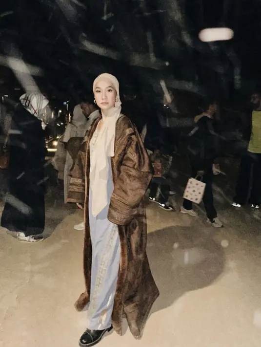 Ia juga mengenakan hijab turban coklat yang dipadukan gamis warna biru dan outer panjang warna coklat yang membalut tubuhnya.  [@itsmebcl]