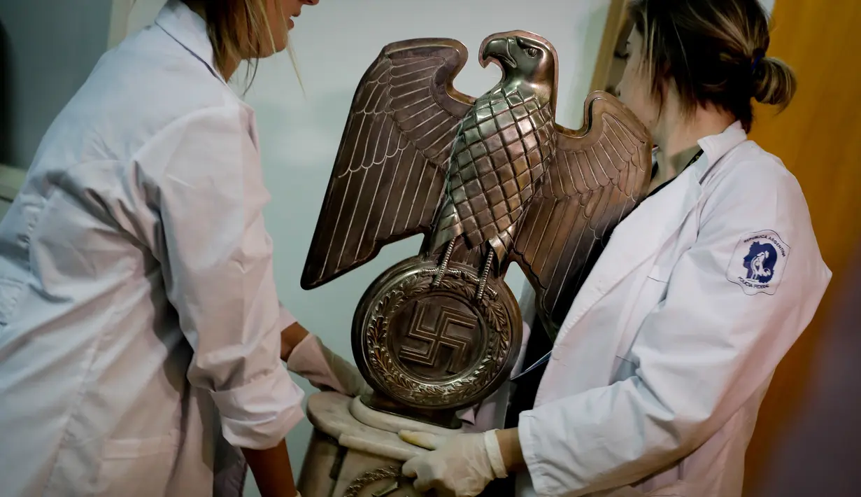 Anggota polisi federal memegang patung burung Nazi yang berhasil ditemukan di markas besar Interpol, di Buenos Aires, Argentina, (16/6). (AP Photo/Natacha Pisarenko)