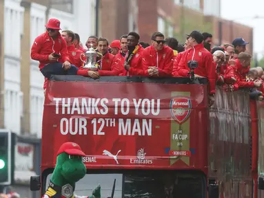 Para Pemain Arsenal berada diatas bus melakukan parade keliling kota untuk merayakan kemenangan usai meraih Piala FA di London, Inggris, (31/5/2015). Arsenal meeraih Trofi piala FA usai mengalahkan Aston Villa 4-0. (REUTERS/Neil Balai)