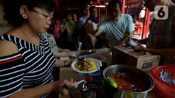 Pengurus Vihara Kim Tek Ie menyiapkan menu makan siang untuk pembeli warung nasi kuning Podjok Halal di Petak Sembilan, Jakarta, Selasa (24/12/2019). Warung ini merupakan cabang kesembilan sejak didirikan pada 6 Febuari 2018 lalu. (merdeka.com/Imam Buhori)