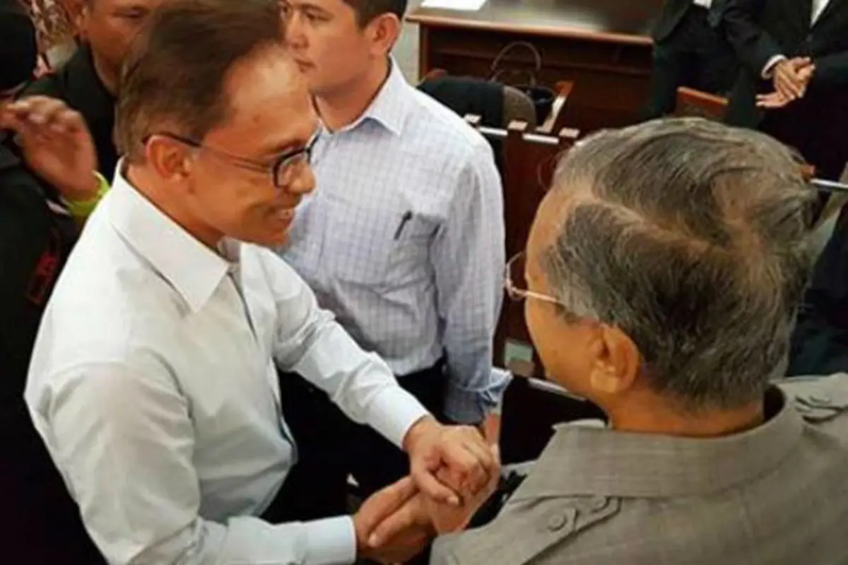 Anwar Ibrahim (kiri) dan Mahathir Mohamad tampak berjabat tangan di Pengadilan Tinggi Kuala Lumpur