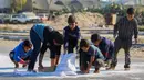 Anak laki-laki Palestina mengais tepung dari jalan setelah sebuah tas jatuh dari truk bantuan yang melaju di jalan Salaheddin di Deir el-Balah di Jalur Gaza tengah pada 5 November 2024. (Eyad BABA/AFP)