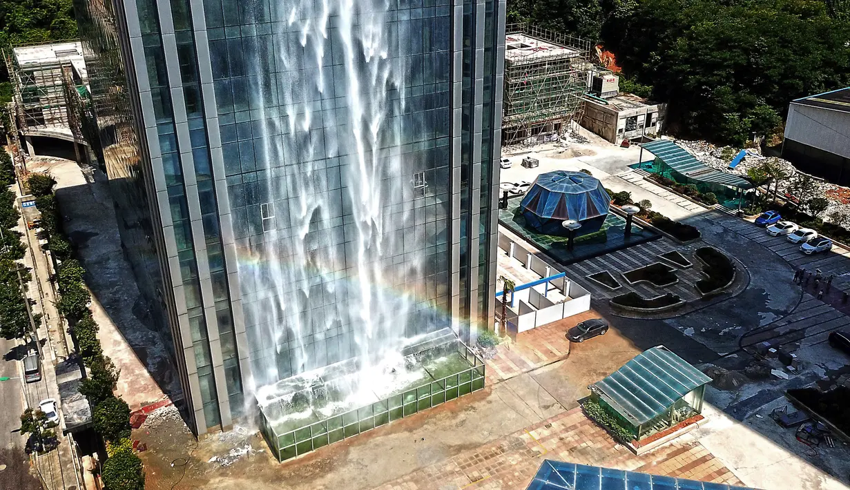 Pelangi tercipta dari air terjun yang mengalir di sisi gedung Liebian International Plaza di Kota Guiyang, China, 20 Juli 2018. Air terjun ini dikelola oleh Guizhou Ludiya Property Management Co., dan dirancang untuk menjadi objek wisata. (AFP/China OUT)