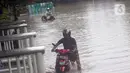 Pengendara mendorong kendaraannya saat melintasi Jalan Di Panjaitan dekat Halte Transjakarta Cawang Soetoyo yang banjir, Jakarta, Rabu (1/1/2020). Hujan yang mengguyur Jakarta sejak Selasa sore (31/12/2019) mengakibatkan banjir di sejumlah titik di Jakarta. (Liputan6.com/Helmi Fithriansyah)