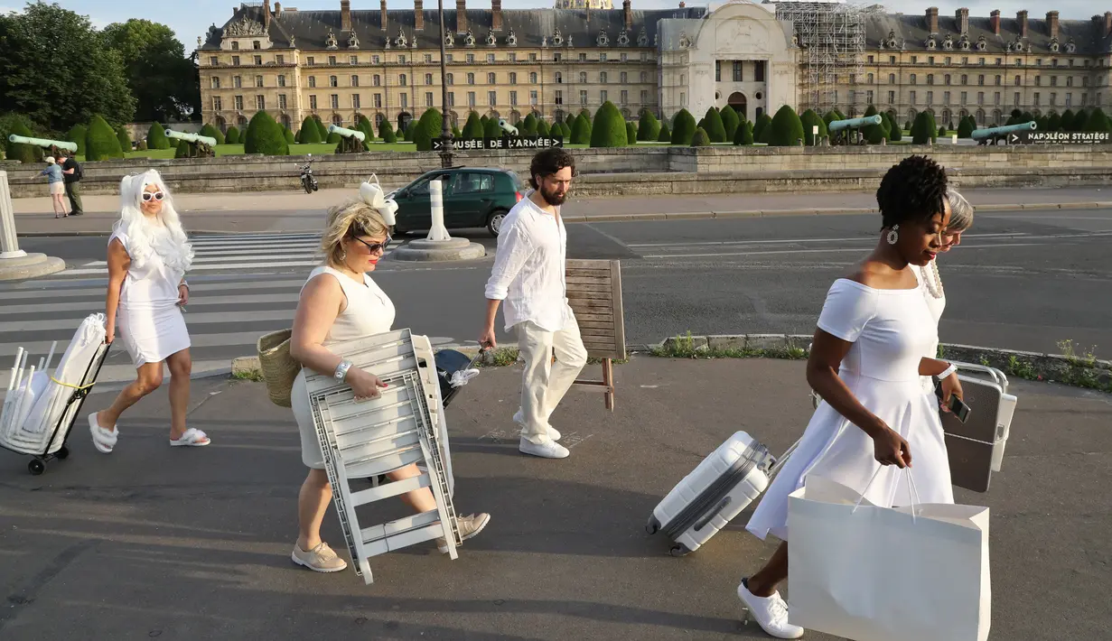 Sejumlah orang berpakaian putih membawa peralatan dan kursi untuk mengikuti makan malam bersama atau "Diner en Blanc" yang ke-30 di Paris, Prancis (3/6). (AFP/Francois Guillot)